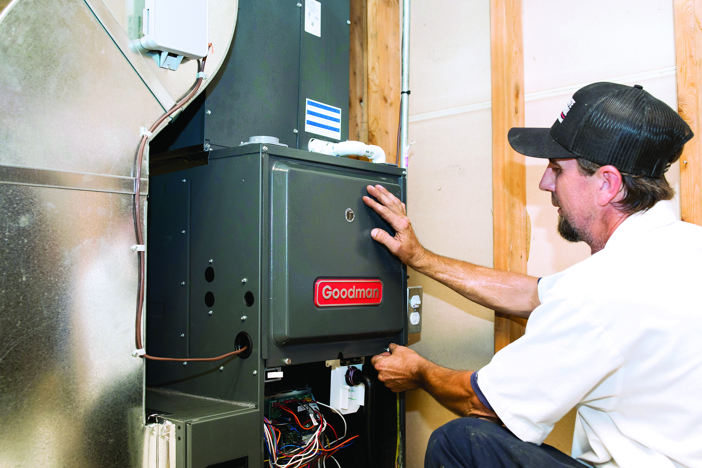 Technician working beside a residential furnace in a utility space.