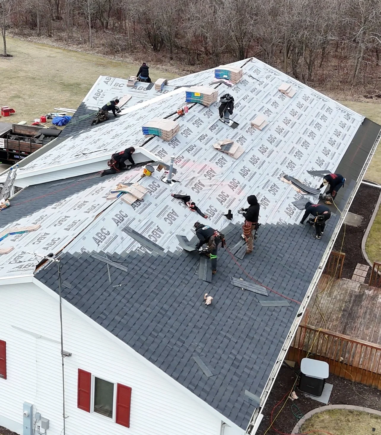 Crew installing shingles across a residential roof as part of a complete replacement.